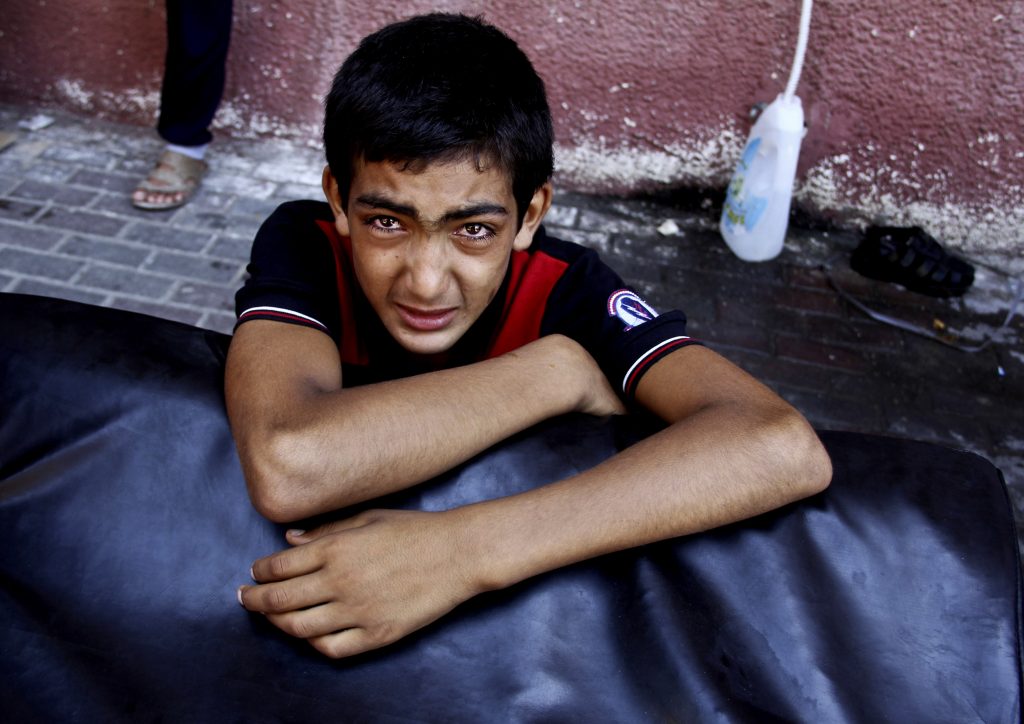 A Palestinian boy cries after watching his wounded relatives being rushed to emergency rooms at the Nasser hospital following an Israeli air strike in Khan Younis, the southern Gaza Strip, Thursday, July 24, 2014. Israeli troops backed by tanks and aerial drones clashed with Hamas fighters armed with rocket-propelled grenades and assault rifles on the outskirts of Khan Younis, killing many militants, according to a Palestinian health official. Hundreds of people fled their homes as the battle unfolded, flooding into the streets with what few belongings they could carry, many with children in tow. They said they were seeking shelter in nearby U.N. schools. (AP Photo/Hatem Ali)