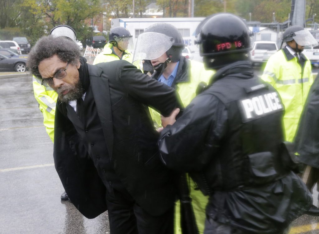 Philosopher Cornel West, center, is taken into custody after performing an act of civil disobedience at the Ferguson, Mo., police station Monday, Oct. 13, 2014, as hundreds continue to protest the fatal shooting of 18-year-old Michael Brown by police in August. In fact, tensions escalated last week when a white police officer shot and killed 18-year-old Vonderrit Myers Jr., who authorities say shot at police before he was killed. (AP Photo/Charles Rex Arbogast)