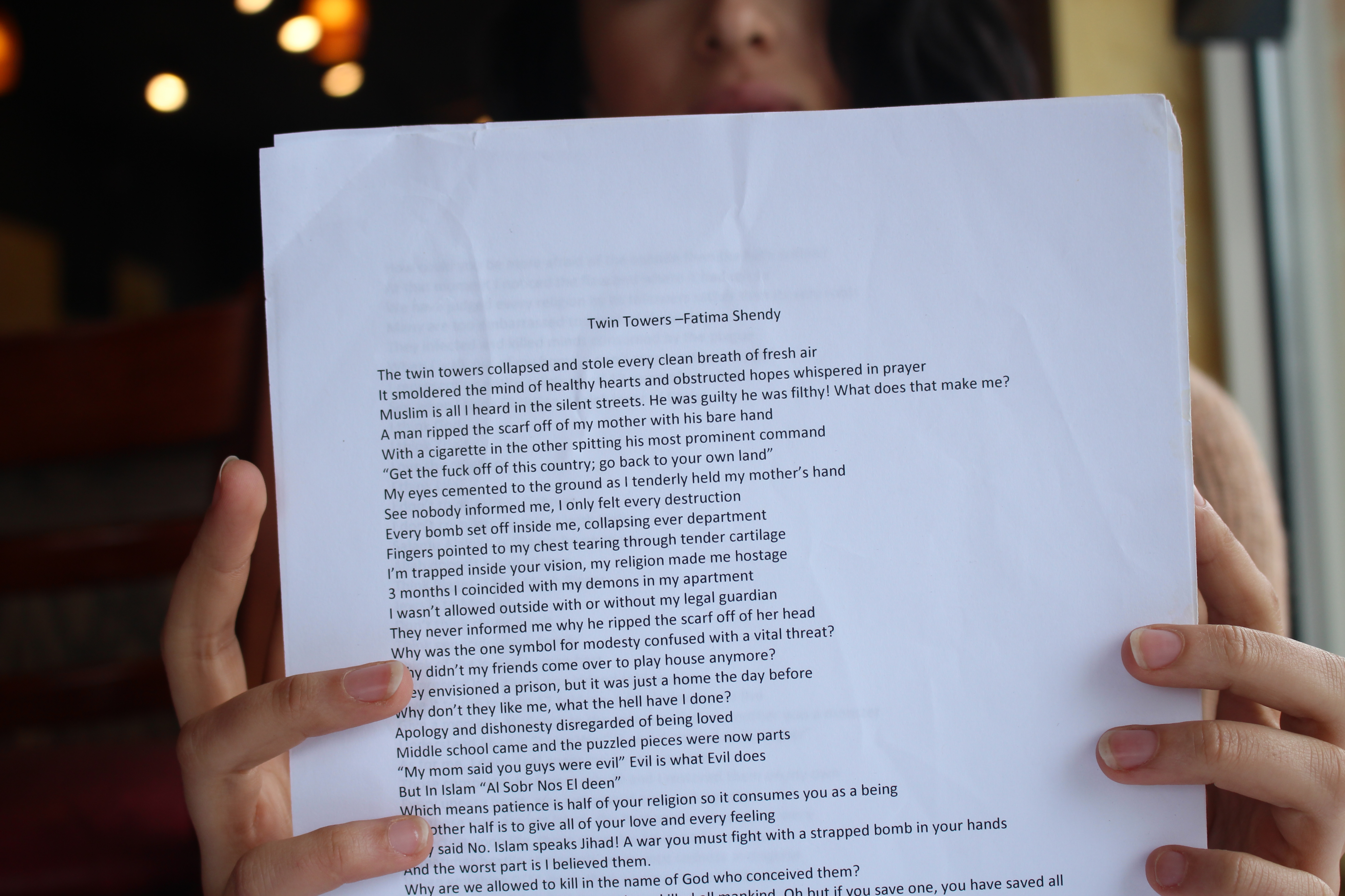22-year-old Fatima Shendy holds up her poem titled “Twin Towers,” which she performed around a small group of people.